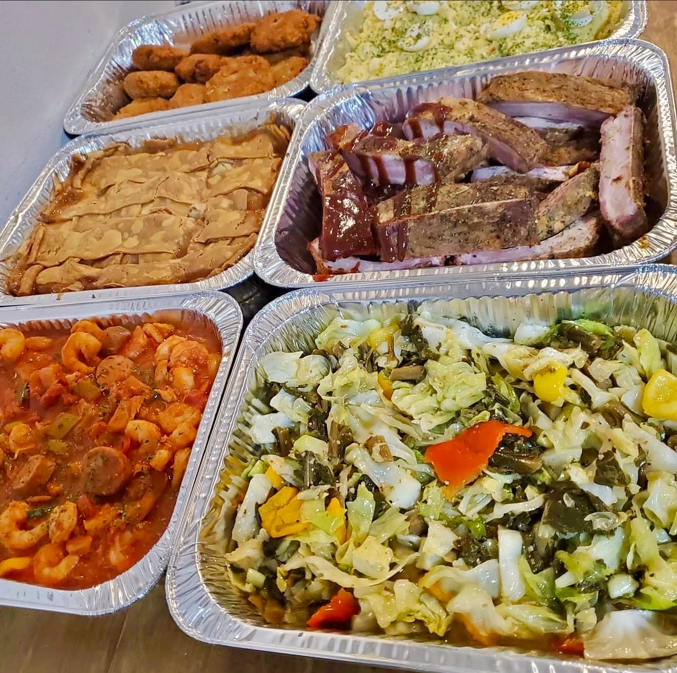 Overhead wedding catering spread with ribs, jambalaya, cabbage, hush puppies, potato salad, and Southern sides